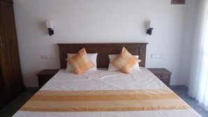 Een hotelkamer met een groot bed, twee nachtkastjes en twee wandlampen.
