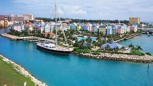 Un port de plaisance avec des bâtiments aux couleurs vives, un yacht amarré et un espace piscine.