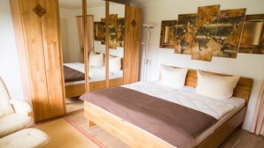 Un dormitorio con una cama de madera, una silla, un espejo y un mapa mundial en la pared.