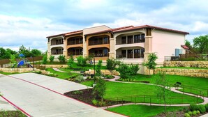 A multi-story building with balconies, a playground, and landscaped gardens. - Gorgeous views of the rural surroundings! (Marble Falls)