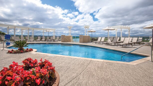 A pool area with lounge chairs and umbrellas, surrounded by a pergola structure. - Gorgeous views of the rural surroundings! (Marble Falls)