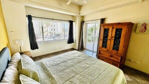 Ein Schlafzimmer mit einem großen Bett, einem Holzschrank und einem Fenster mit Vorhängen.