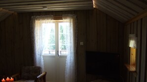 A cozy room with wooden walls, a wooden table with candles, a chair, and a television. - Idyllic place for a relaxing holiday (Årjäng)
