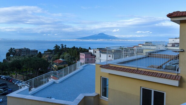 Eine Dachterrasse mit Blick auf das Meer und ein Berg in der Ferne.