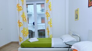 Ein Hotelzimmer mit Bett, einem kleinen Tisch, einem Stuhl und einem Balkon mit Geländer.