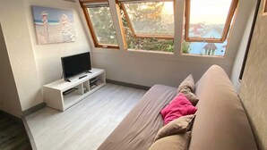 Un soggiorno moderno con divano, televisore a schermo piatto e un quadro appeso al muro. Tre finestre garantiscono luce naturale.