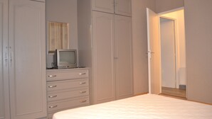 Una camera da letto con un letto, una cassettiera, una televisione e un armadio.