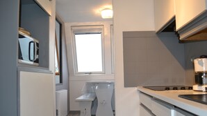 Una cucina compatta con una finestra, una panca integrata e un fornello.