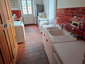Eine kleine Küche mit einer weißen Spüle, einem weißen Kühlschrank und einer gefliesten Rückwand.
