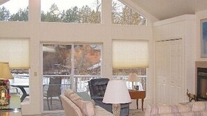 A spacious living room with large windows, a fireplace, and a view of the outdoors.