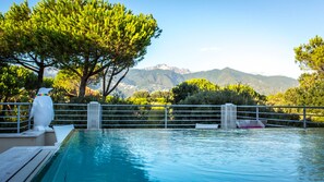 Una piscina con vistas a montañas, una escultura blanca y una valla de metal.