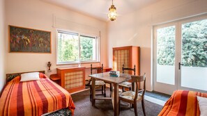 Una habitación con dos camas, una mesa de comedor con sillas, un armario y un cuadro en la pared.