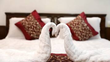 A bed with a white blanket and two pillows with red and gold patterns.