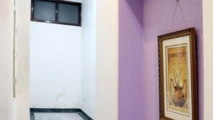 A hallway with a marble floor, a purple accent wall, and a framed picture. - Hotel Heritage Inn (Amritsar)