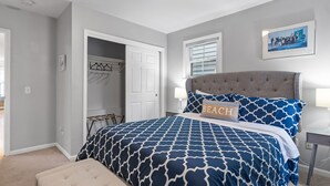 A bedroom with a bed, a nightstand, a chair, a door, and a wall-mounted picture. - Downtown Newport Luxury on Thames, 2BR, Sleeps 6 - Walk to Everything (Newport)