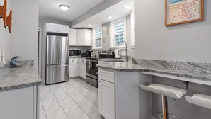 A modern kitchen with white cabinetry, stainless steel appliances, and a marble countertop. - Downtown Newport Luxury on Thames, 2BR, Sleeps 6 - Walk to Everything (Newport)