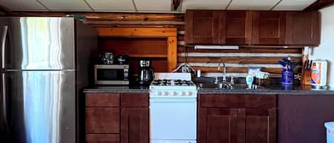 A kitchen with wooden cabinets, a stainless steel refrigerator, a white stove, and a microwave.