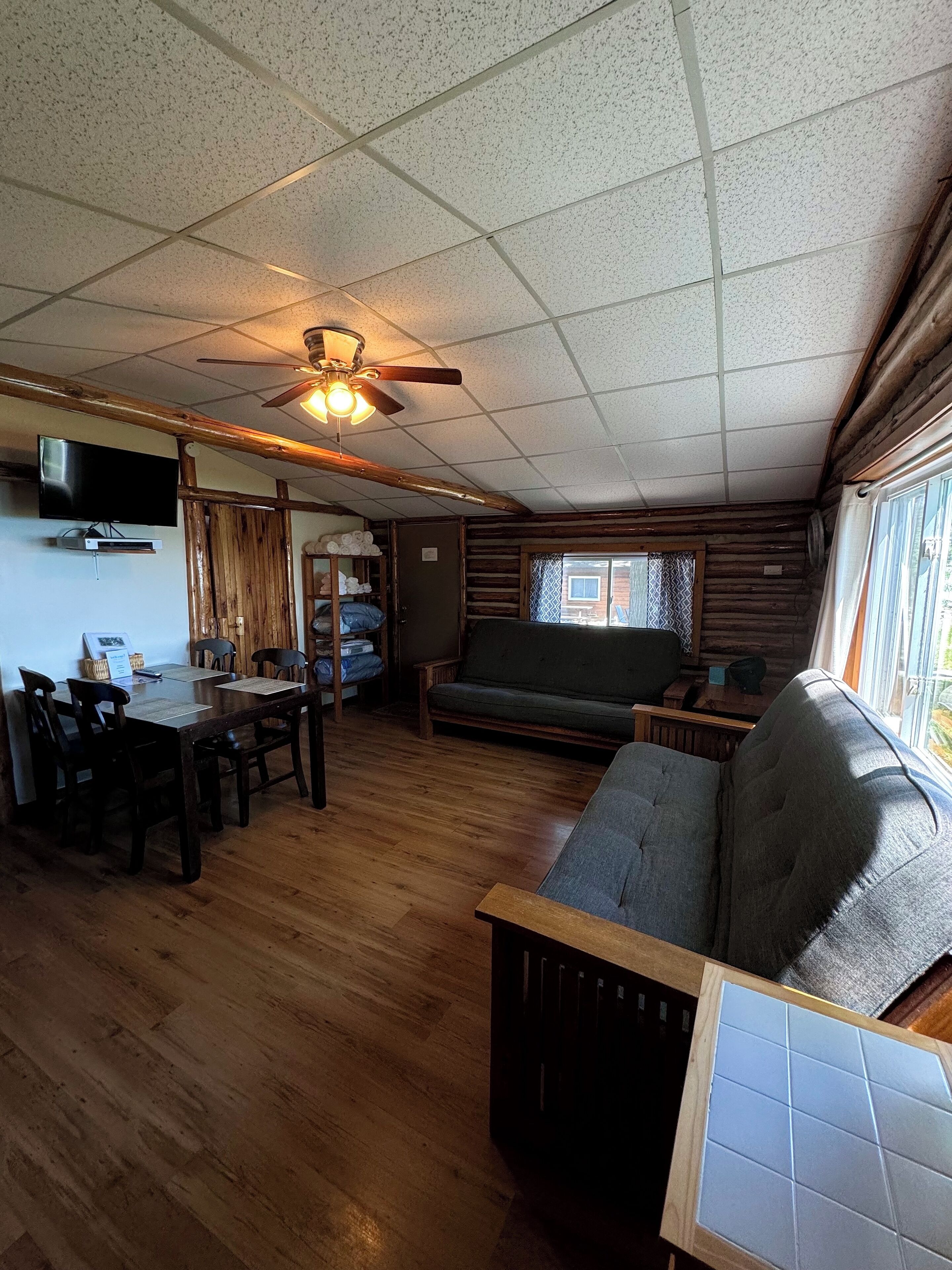 A cozy cabin interior with a dining area, a sofa, and a television.