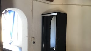 A room with a tiled floor, a black door, and a window with blue curtains.