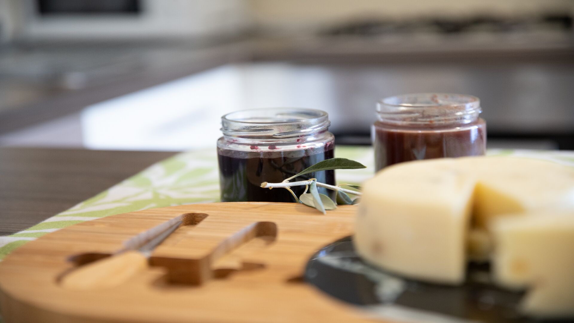 Juustolajitelma, jossa on mukana veitsi, purkki etikkakurkkuja ja purkki chutney-kastiketta, tarjoiltuna puisella leikkuulaudalla.