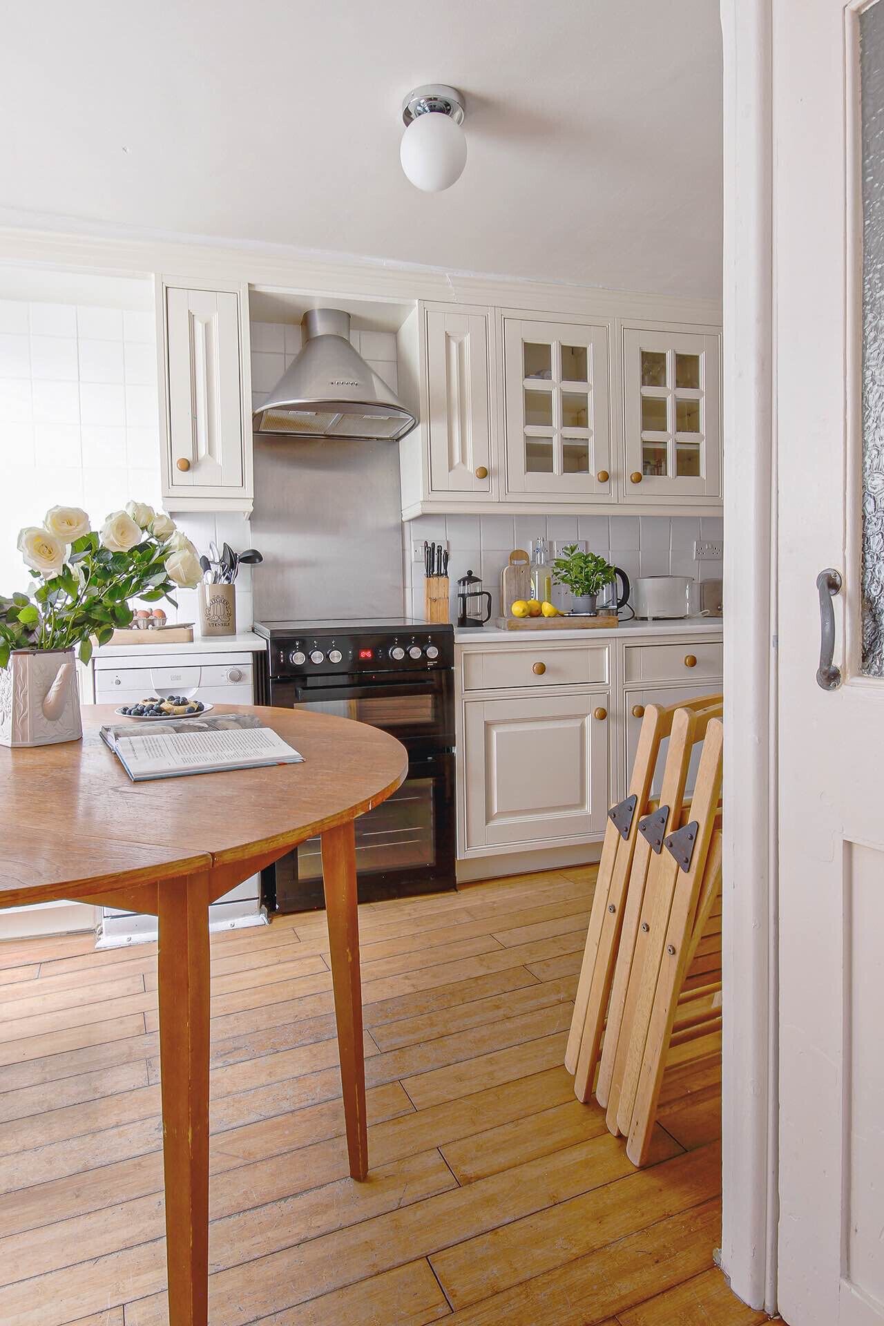 A kitchen with white cabinets, a stove, and a dining table with a plant.