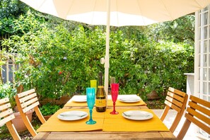 A wooden table with yellow placemats, two wine glasses, and a bottle of wine. - Modern, cosy Garden Suite, parking u.r. (Roma)