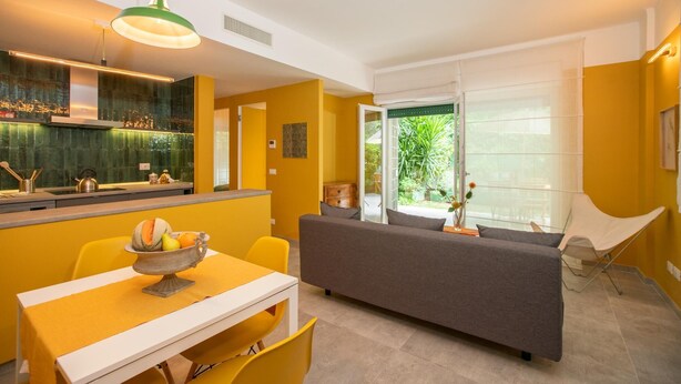 A modern kitchen with a dining area, a sofa, and a chair. - Modern, cosy Garden Suite, parking u.r. (Roma)