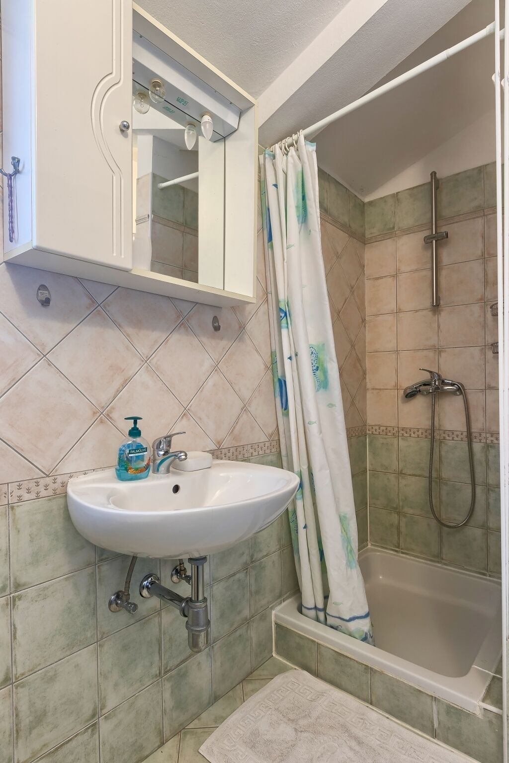 A bathroom with a white sink, a mirror above it, a shower with a curtain, and a bathtub.