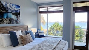 Un dormitorio con una cama grande, vista al mar y un cuadro en la pared.
