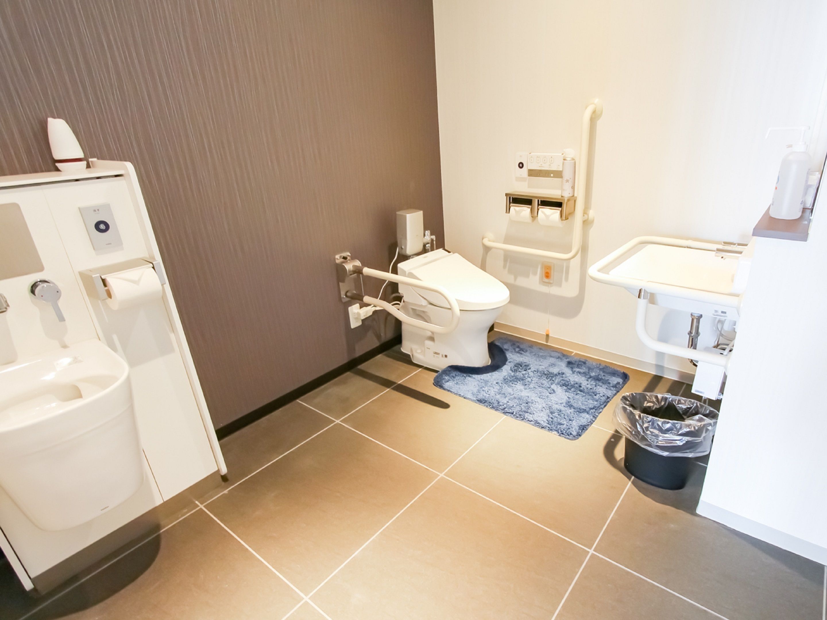 Een badkamer met toilet, bidet, wastafel en een prullenbak.