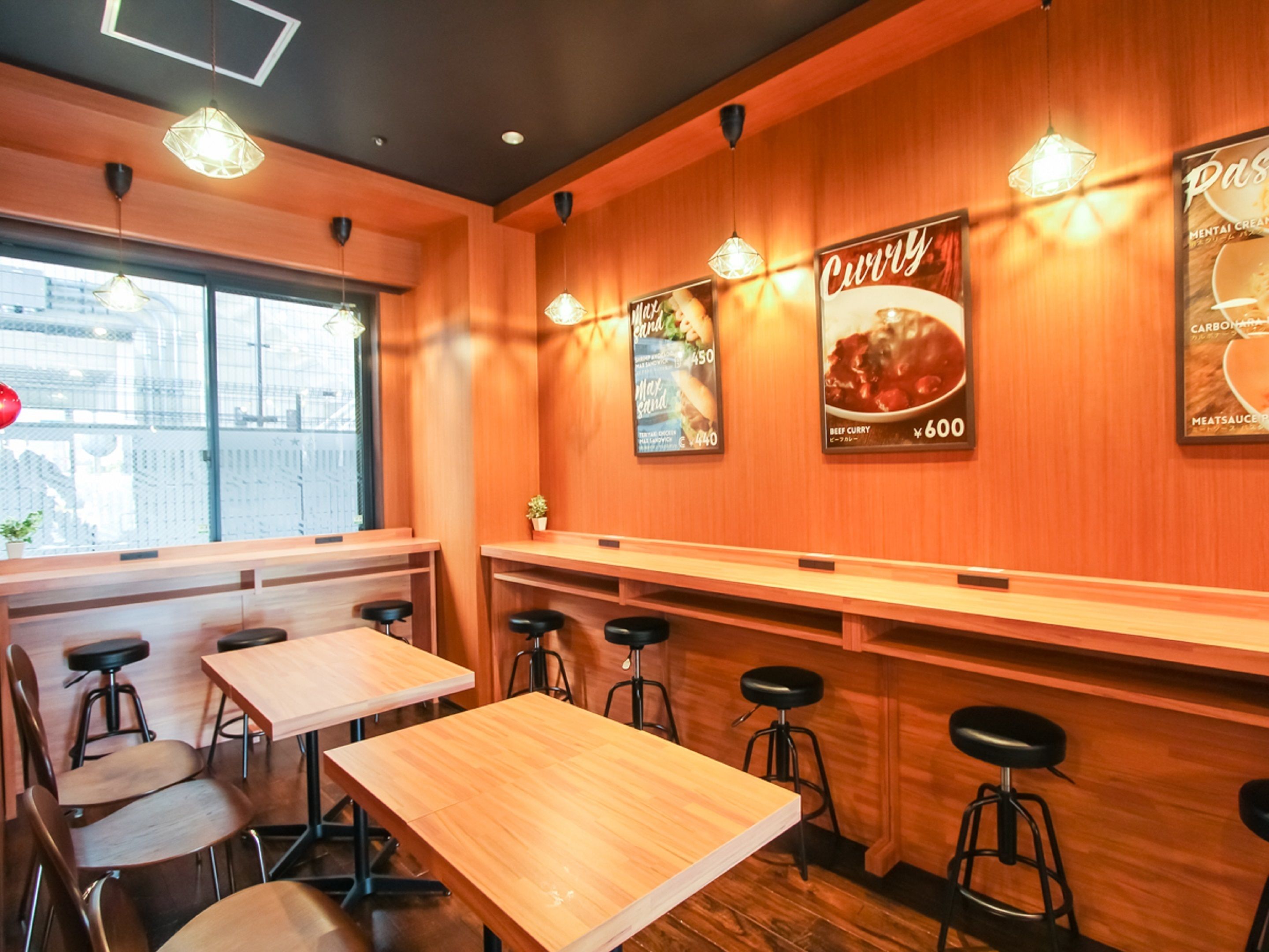 A restaurant interior with wooden walls, tables, and stools. There are posters on the walls advertising dishes.