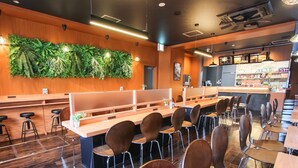 A modern restaurant with wooden flooring, a green wall with plants, and a bar area. - HOTEL LiVEMAX PREMIUM Himejieki-Minami (Himeji)