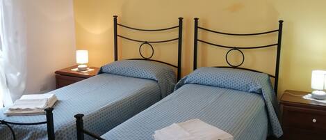 A room with two beds, a painting of candles, and a chandelier.