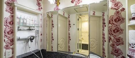 A bathroom with a large mirror, a sink with a faucet, and a shower area.