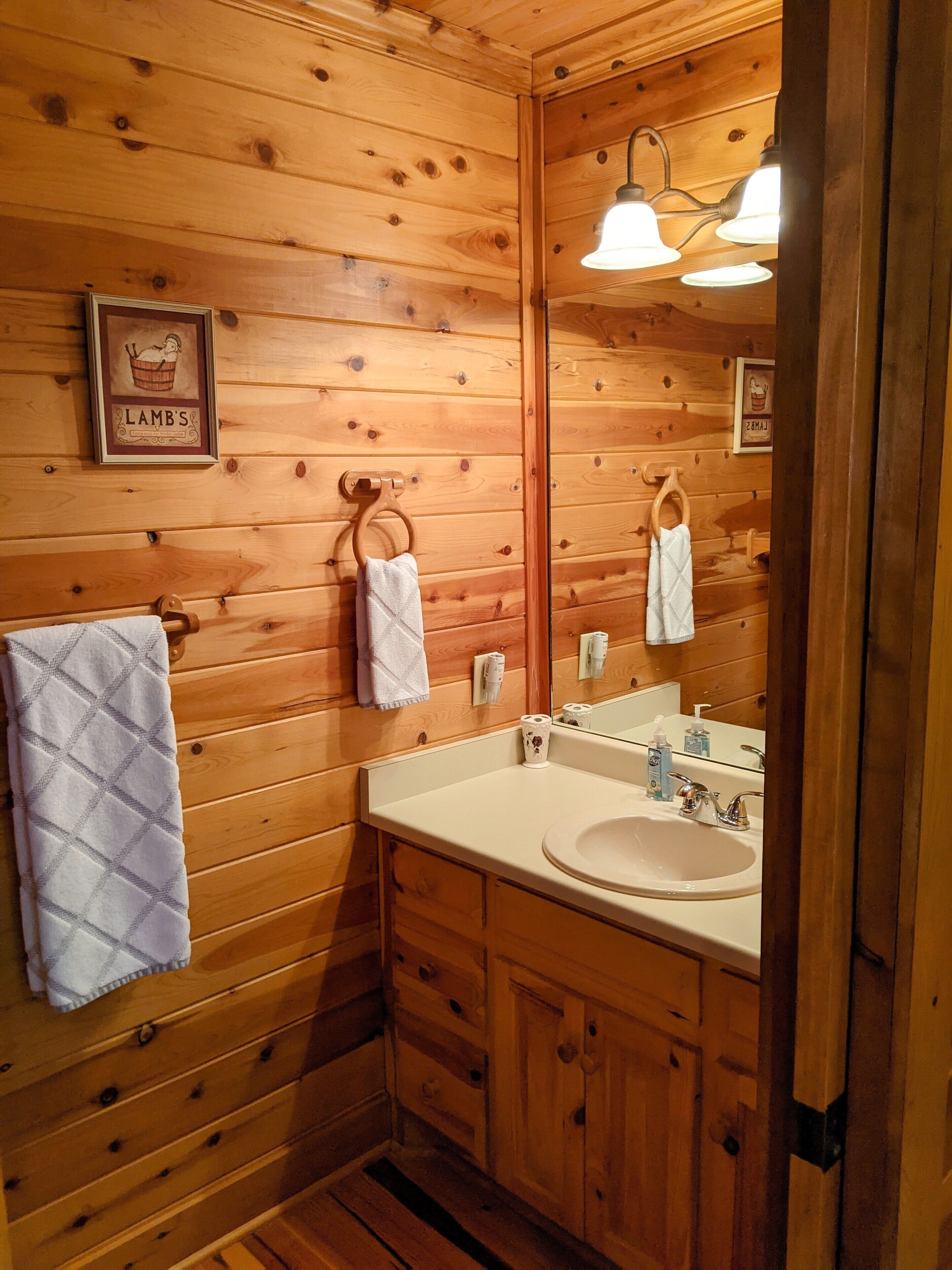 Un baño de estilo cabaña de madera con lavamanos doble, armarios de madera y un espejo grande.