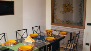 A dining area with a glass table, black chairs, and yellow plates.