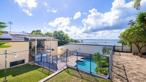 En boligejendom med swimmingpool, overdækket terrasse og havudsigt.