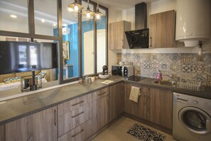Cozinha moderna com armários de madeira, micro-ondas embutido, máquina de lavar e painel de azulejos.