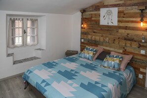 A bedroom with a bed, a window with curtains, a wooden wall, and a dreamcatcher. - Nice apartment in the city center, quiet. Elevator. (Corte)
