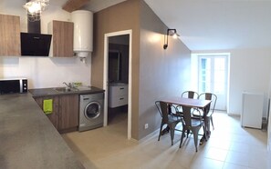 A compact kitchen with a washing machine, a dining area with four chairs, and a built-in oven. - Nice apartment in the city center, quiet. Elevator. (Corte)