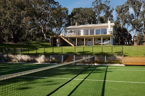 Un edifici residencial amb una pista de tennis al davant.