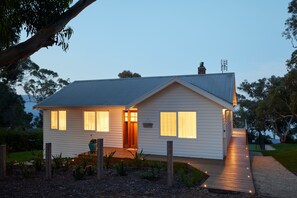 A single-story house with a sloped roof, a front porch, and a pathway leading to the entrance. - The White House Ocean Views Tennis Court in Lorne (Lorne)