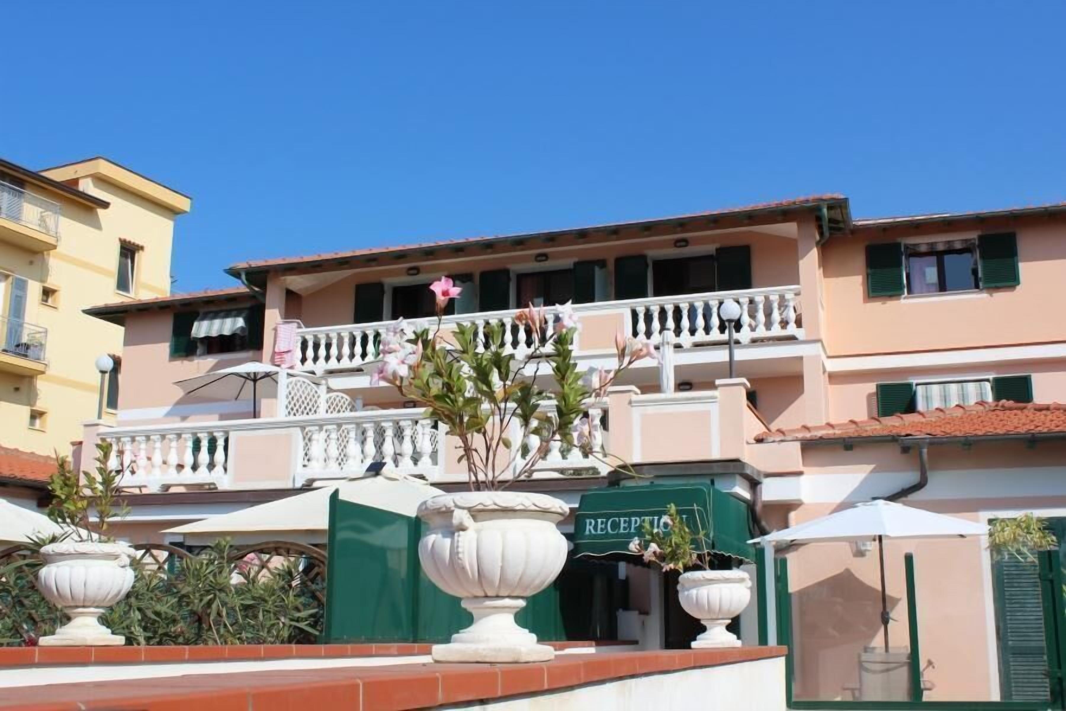 A hotel with a reception area, outdoor seating, and a balcony with flowers.