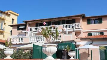Un hotel con reception, area salotto all'aperto e un balcone fiorito.