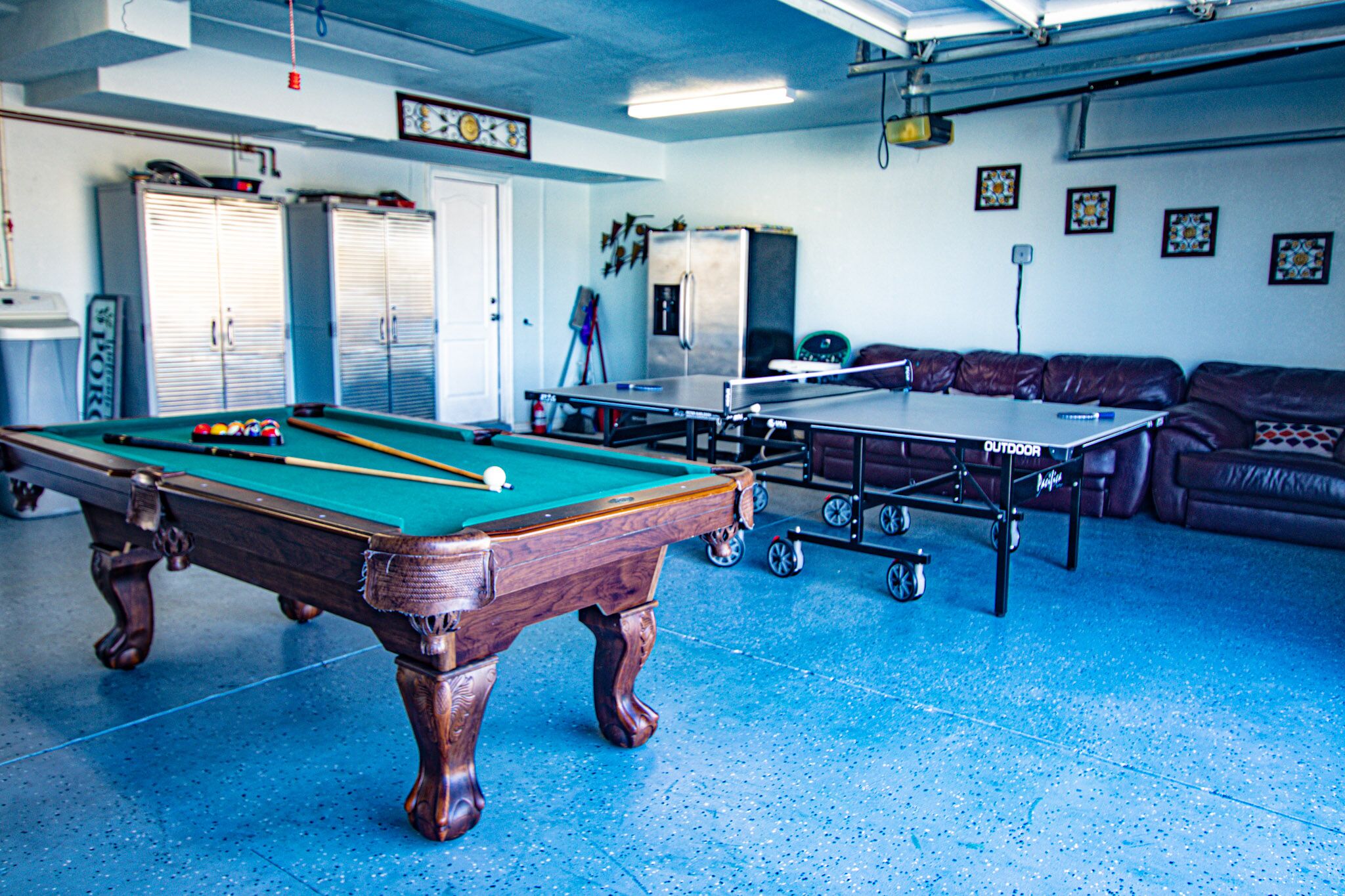 A pool table, a ping pong table, and a billiards table in a room with a blue floor.