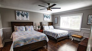 A bedroom with two beds, wooden flooring, a ceiling fan, and artwork on the walls. - FAMILY HOME W/POOL & BBQ NEAR LAS VEGAS STRIP 9 MINS (Las Vegas)