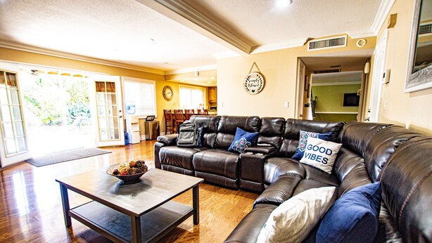 A living room with a leather sofa, a coffee table, and a dining area in the background. - FAMILY HOME W/POOL & BBQ NEAR LAS VEGAS STRIP 9 MINS (Las Vegas)