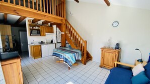 Ein gemütliches Wohnzimmer mit einer Holztreppe, einem Essbereich und einer Küche mit modernen Geräten.