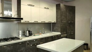 Uma cozinha moderna com bancada branca, eletrodomésticos de aço inoxidável e armários escuros.