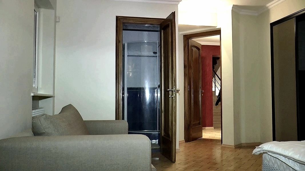 A room with a sofa, a bed, and a door leading to a staircase.